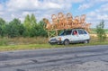 Ukrainian craftsman with own wicker-work on a roof of small car doing short stop on a roadside