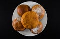 Ukrainian donuts on a white plate on a black background. View from above.