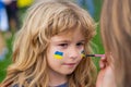 Ukrainian flag on child cheek. Human protest.