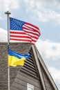 Ukrainian flag flying beneath American flag on windy day at residential home - Close-up Royalty Free Stock Photo