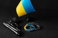 Ukrainian flag and handcuffs on black background, concept of crime and justice in the country Royalty Free Stock Photo