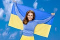 Ukrainian girl carries blue and yellow flag of Ukraine fluttering on the blue sky background. Royalty Free Stock Photo