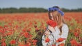 Ukrainian girl collecting and smelling a bouquet of poppies in a field of poppies. Royalty Free Stock Photo