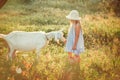 Ukrainian girl on a farm feeds a goat. Cute little girl with long blonde hair at sunny sunset spends time with a pet. Cute baby 6 Royalty Free Stock Photo