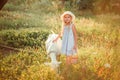 Ukrainian girl on a farm feeds a goat. Cute little girl with long blonde hair at sunny sunset spends time with a pet. Cute baby 6 Royalty Free Stock Photo