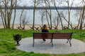 Ukrainian girl sitting on bench and looking at anti-tank hedgehogs on sea shore. Militrary invasion of Russia in Ukraine 2022