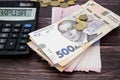 Ukrainian hryvnia with coins and calculator on a wooden background. The word `risse` on the scoreboard calculator. The concept of