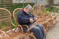 Ukrainian man cut sleeving while making whicker rocking chair in summer garden