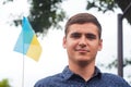Ukrainian man. Young smile man holding ukrainian flag. No war. Support for Ukraine. Patriotic Spirit rising hand of Ukraine flag.
