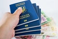 Ukrainian passports in hand against the background of hryvnia. Close-up. Royalty Free Stock Photo