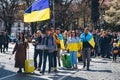 Ukrainian people walk with Ukrainian flags on the street.