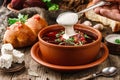 Ukrainian and Russian traditional beetroot soup or borscht in bowl with rib eye meat, buns, parsley on wooden rustic background. Royalty Free Stock Photo