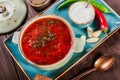 Ukrainian and Russian traditional beetroot soup - borscht in clay pot with sour cream, garlic, herbs and bread on background Royalty Free Stock Photo