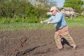 Ukrainian senior peasant working with hand plough in kitchen garden