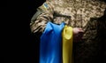 Ukrainian soldier holds a flag of the independent state of Ukraine. Steadfastness and courage of the people in the fight against
