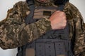 Ukrainian soldier in military pixel unform and bulletproof vest and arm near hart.