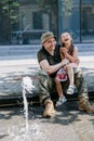 Ukrainian soldier returning from the war meets his happy little daughter and cheerful playing with her near fountain in city