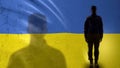 Ukrainian soldier silhouette standing against national flag, proud army sergeant