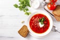 Ukrainian soup with bread, tomato, borscht with sour cream and parsley in a white plate top view