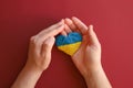 Ukrainian Ukraine flag, no war. Heart shape of blue and yellow plasticine modeling clay in male hands on red maroon texture Royalty Free Stock Photo
