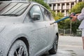 Ukrainian woman with foam water gun cleans her car in service Royalty Free Stock Photo