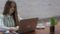 A Ukrainian woman of a young age freelances remotely using her computer at a cafe.