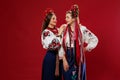 Ukrainian women in traditional ethnic clothing and floral red wreath on viva magenta studio background. National embroidered dress Royalty Free Stock Photo