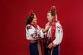 Ukrainian women in traditional ethnic clothing and floral red wreath on viva magenta studio background. National embroidered dress Royalty Free Stock Photo