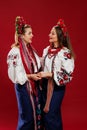 Ukrainian women in traditional ethnic clothing and floral red wreath on viva magenta studio background. National embroidered dress Royalty Free Stock Photo