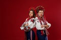 Ukrainian women in traditional ethnic clothing and floral red wreath on viva magenta studio background. National embroidered dress Royalty Free Stock Photo