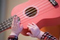 Baby fingers plays guitar. Ukulele strings and frets Royalty Free Stock Photo