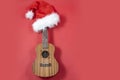 Ukulele with copy space Christmas guitar on a red background. Christmas hat. An invitation to a New Year's musical Royalty Free Stock Photo