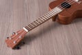 A ukulele lies on a woody background out of focus without people a place to record