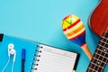 Ukulele with maracas, opened spiral notebook, pen and earphones Royalty Free Stock Photo