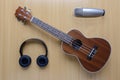 Ukulele and microphone and headphone on wooden floor background