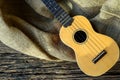 The Ukulele on a rustic table with burlap sacking on wooden back Royalty Free Stock Photo