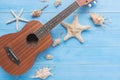 Ukulele and sea shell on light blue wood plank floor for summer