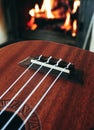 Ukulele small guitar close up stings, fireplace on the background. Musical concept, guitar fret board macro, fire in chimney, cos Royalty Free Stock Photo