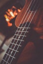 Ukulele small guitar close up stings, fireplace on the background. Musical concept, guitar fret board macro, fire in chimney, cos Royalty Free Stock Photo