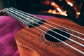 Ukulele small guitar close up stings, fireplace on the background. Musical concept, guitar fret board macro, fire in chimney, cos Royalty Free Stock Photo