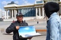 Ulaan Baatar, Mongolia - 05.11.2022: Mongolian man shows souvenirs to a tourist for sale