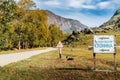 Signpost banner with the inscription: `Tourist parking` near a dirt road in the Chulyshman valley