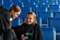 ULAN-UDE, RUSSIA - JANUARY 2020: Two smiling teenage girls waiting at the empty airport on blue chairs