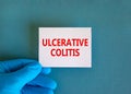 Ulcerative colitis symbol. White note with words Ulcerative colitis, beautiful blue background, doctor hand in blue glove. Medical