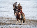 Beautiful young Mongolian golden eagle hunter on horseback releases her eagle into the wild, a dynamic hunting scene with an eagle
