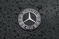 Ulm, Baden-wuerttemberg, Germany - May 16, 2023: Close up of a Mercedes-Benz car logo on black metallic surface with rain drops. Royalty Free Stock Photo