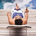 The ultimate in relaxation. Rear view shot of a young man lounging be the pool with a beer.