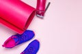 Ultra blue violet pink female sneakers, yoga mat, water bottle on pastel pink background flat lay top view with copy space. Sports