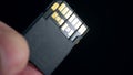 Ultra high speed UHS II SD card in fingers on dark background. Macro close-up
