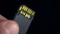 Ultra high speed UHS II SD card in fingers on dark background. Macro close-up